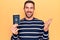 Young handsome tourist man holding united states passport over isolated yellow background celebrating achievement with happy smile
