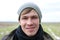 Young handsome unshaven guy close-up face portrait on a spring field background with green grass