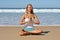 Young handsome woman meditating on the beach