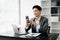 Young handsomel man using laptop and tablet while sitting at her working place. Concentrated at work. in office