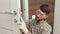 Young handyman in uniform fixing door lock.