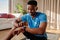 Young happy African American Black male working out at home on yoga mat checking smart watch. Maintaining his fitness