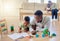Young happy african american father helping his son with homework while sitting on the floor at home. Little boy focused