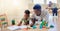 Young happy african american father helping his son with homework while sitting on the floor at home. Little boy focused