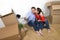 Young happy American couple sitting on floor taking selfie photo celebrating moving in new house or apartment