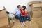 Young happy American couple sitting on floor taking selfie photo celebrating moving in new house or apartment