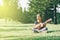 Young and happy asian girl playing ukelele guitar in the park at sunny morning while looking to copy space