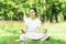 Young happy asian woman sitting on grass at park ,wearing earphones listening to music relaxing with coffee  .Nature essential