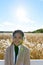 Young happy Asian woman smiling against scenic view of autumn bulrush field