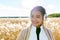 Young happy Asian woman smiling while thinking against scenic view of autumn bulrush field