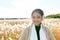 Young happy Asian woman smiling while thinking against scenic view of autumn bulrush field