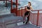 Young happy athletic slim beautiful woman have a rest and standing on stairs after doing cardio interval training in black