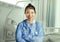 Young happy and attractive Asian Chinese medicine doctor woman in blue scrubs smiling cheerful at hospital room bed in health care