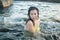Young happy and attractive Asian woman in the sea - cheerful and carefree Japanese girl playful in the water during Summer