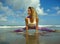 Young happy and attractive girl doing flexibility exercise with legs split  on sand in wellness harmony health care and fitness