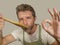 Young happy and attractive home cook man in apron cheerful and charming tasting stew with spoon isolated on even background