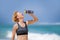 Young happy and attractive sport runner woman drinking water bottle or isotonic drink after running workout at tropical paradise b