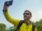 Young happy and attractive sporty hiker man with trekking backpack hiking at mountain taking selfie enjoying travel getaway