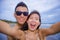 young happy and beautiful Asian Chinese couple taking selfie photo with mobile phone camera smiling joyful having fun on the beach