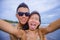 young happy and beautiful Asian Chinese couple taking selfie photo with mobile phone camera smiling joyful having fun on the beach