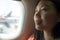 Young happy and beautiful Asian Chinese tourist woman smiling excited sitting in airplane by the window arriving destination in