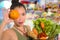 Young happy and beautiful Asian Chinese woman holding basket full of fresh vegetables and fruits smiling cheerful buying healthy