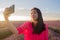 Young happy and beautiful Asian Chinese woman in Summer dress taking sunset selfie with mobile phone at purple lavender flowers