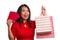 Young happy and beautiful Asian girl in red dress smiling cheerful holding shopping bags as excited spending money after receiving