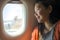 Young happy and beautiful Asian Japanese tourist woman smiling excited sitting in airplane by the window arriving destination in