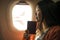 Young happy and beautiful Asian Japanese tourist woman smiling excited sitting in airplane by the window holding passport in