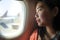 Young happy and beautiful Asian Korean tourist woman smiling excited sitting in airplane by the window arriving destination in