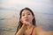 Young happy and beautiful Asian Korean tourist woman taking self portrait selfie with mobile phone smiling having fun at sunset be