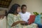 Young happy and beautiful black African American couple in love enjoying at living room sofa couch with laptop computer laughing