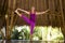 Young happy and beautiful blond American woman doing yoga workout in Bali at exotic bamboo hut opened to the forest in fitness and