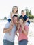 Young happy beautiful Caucasian family having holidays on the beach smiling with mother and father carrying little son and young a