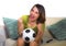 Young happy and beautiful football fan woman watching television game sitting on sofa couch holding soccer ball excited celebratin
