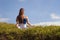 Young happy and beautiful red hair woman sitting on green field relaxed on grass practicing yoga exercise outdoors smiling in