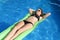 Young happy beautiful woman in bikini and sunglasses lying relax on float airbed at vacation hotel resort swimming pool