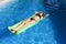 Young happy beautiful woman in bikini and sunglasses lying relax on float airbed at vacation hotel resort swimming pool