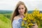 Young happy bride holding bouquet of blooming yellow flowers in countryside. Picture of beautiful happy girl with long light hair