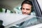 Young happy business man with headphones, shirt and tie sitting in car.