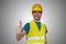 Young happy construction worker in yellow helmet is showing thumbs up gesture