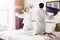 Young happy couple in bathrobe fight pillows on bed