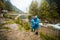 Young happy couple in blue raincoat stand in rain by river