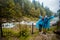 Young happy couple in blue raincoat stand in rain by river