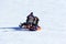 Young happy couple with children riding on an inflatable sledding tubing on a snowy slope, a man shoots a video on a smartphone