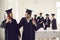 Young happy couple classmates asian girl and caucasian boy celebrating getting diploma