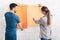 Young happy couple discuss in what color they will paint wall