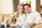 Young happy couple with dog sitting on sofa