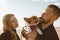 Young happy couple with dog taking selfie photo on beach. Beautiful family and Corgi puppy